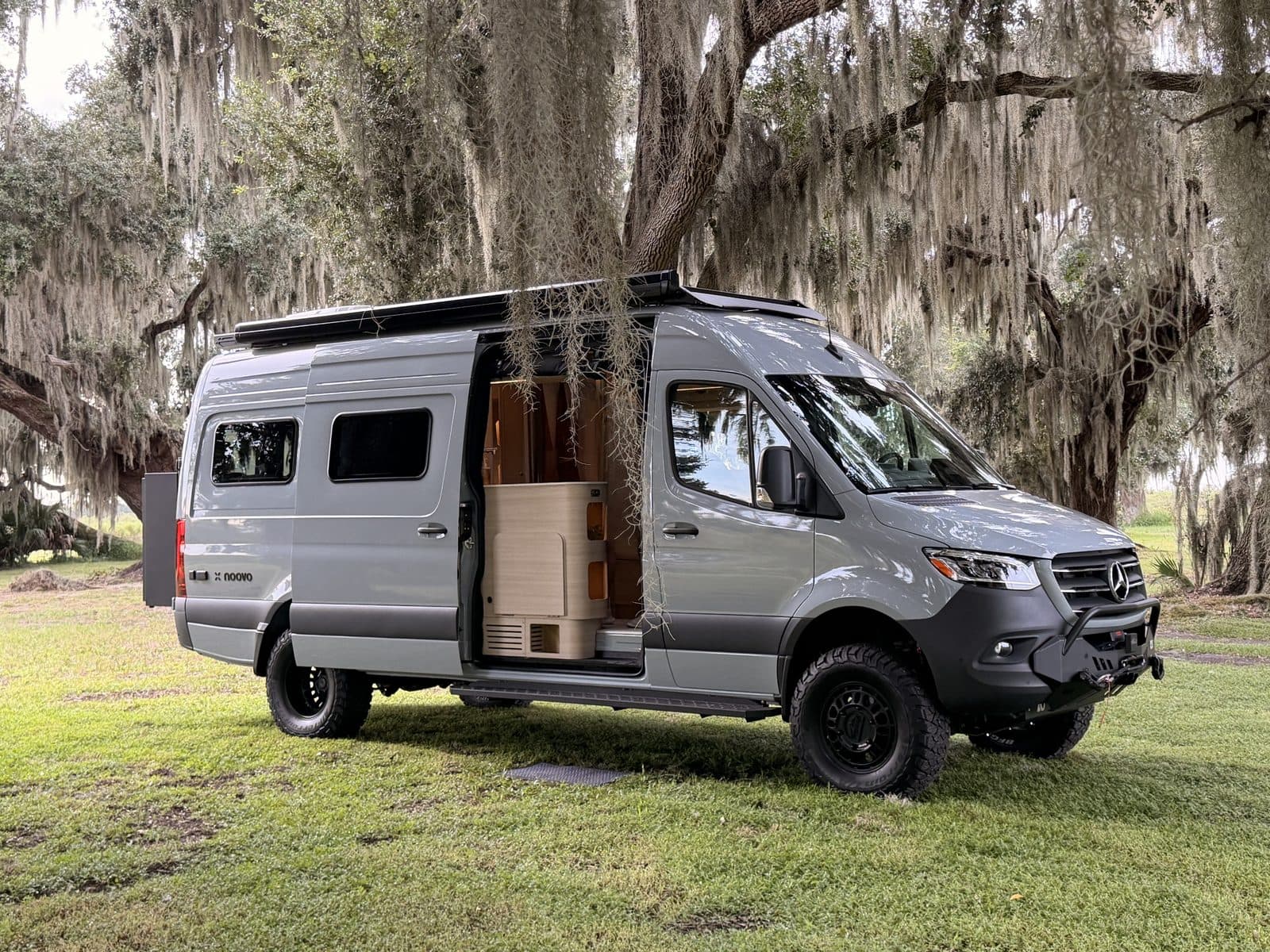 Nellie, our Noovo Next camper van, with the sliding door open under moss-draped live oaks