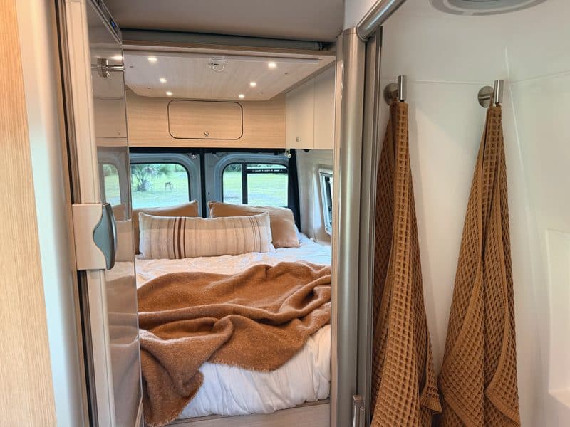 Towels hanging by the shower, with the bed beyond