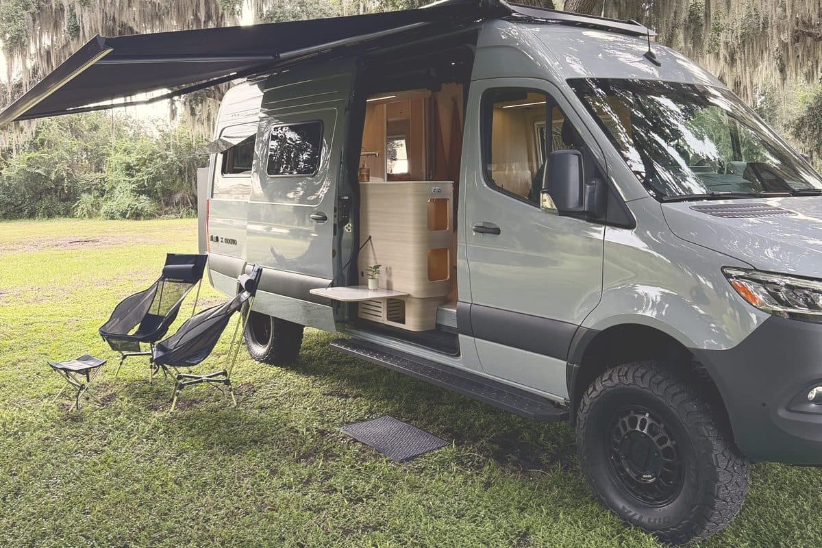 Nellie with the awning out and camp chairs under live oaks