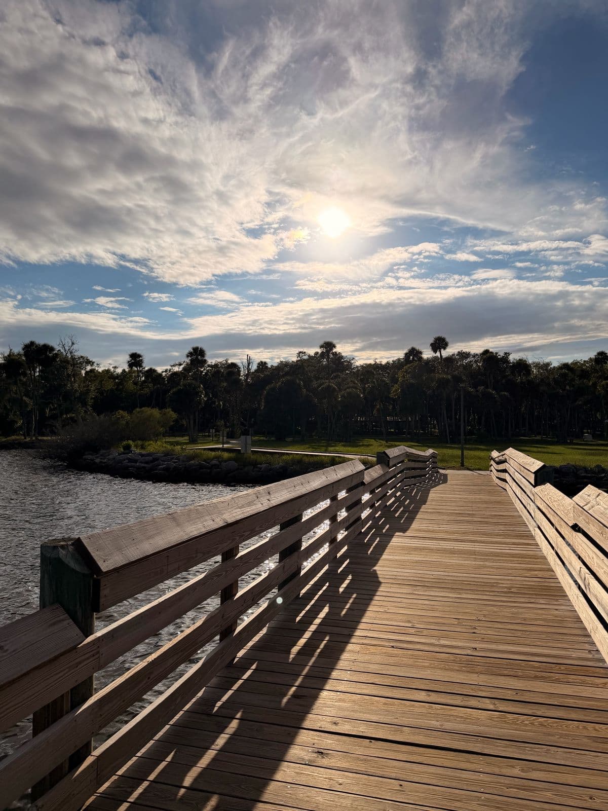 The wooden fishing pier walkway at Manatee Hammock with the sun breaking through clouds